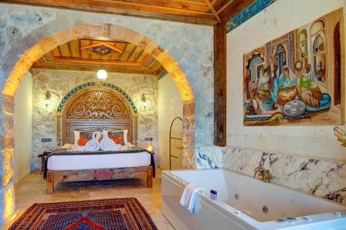 a bedroom with a bed and a bath tub at Kasr-ı Kapadokya Cave Suites in Ortahisar