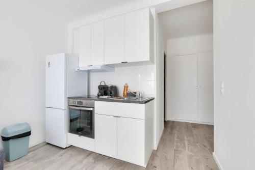 La cuisine blanche est équipée d'un évier et d'un réfrigérateur. dans l'établissement Le Petit Fleury – Balcony, Calm in Cannes, à Cannes