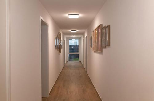 a hallway with white walls and wooden floors and paintings at Mein Träumchen Apartments - 6 grün gemütlich, stilvoll und zentral übernachten in Bielefeld