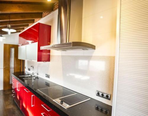 a kitchen with red cabinets and a stove at La Chirumba in Aldeatejada