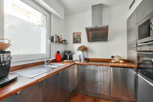 une cuisine avec des placards en acier inoxydable et une fenêtre dans l'établissement L'Écrin d'Azur – Villa, Cinéma & Plage à 50m, à Cannes