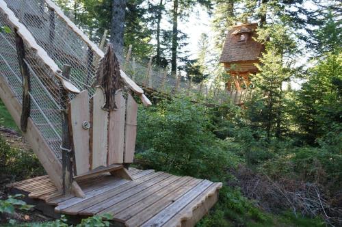 une terrasse en bois avec une maison ornithologique dans les bois dans l'établissement Cabanes des Volcans, à La Tour-dʼAuvergne