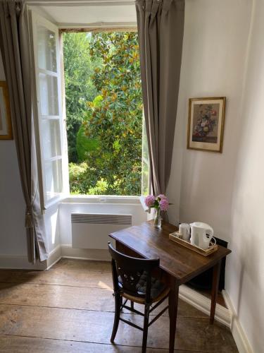 une table et une chaise devant une fenêtre dans l'établissement LA SEIGNEURIE DE TILLAC, à Tillac