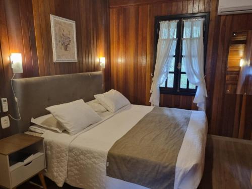 a bedroom with a large bed and a window at Pousada Caliandra Da Serra in Canela