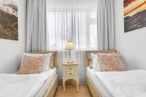 a bedroom with two beds and a table with a lamp at City Comfort Apartments in Reykjavík