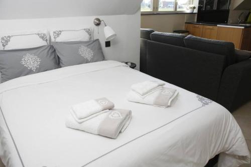 a large white bed with two white towels on it at Au Jardin du Trieu in Pecq