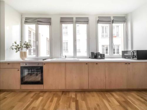 - une cuisine avec des placards en bois et des fenêtres dans l'établissement Suite-appartement 4stars pour 6 à 10 min du Marais, à Paris