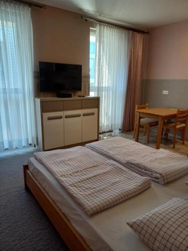 two beds in a room with a television and a table at Pokoje Gościnne Jaga in Kielce