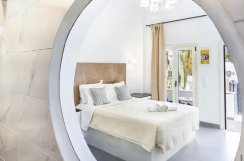 a white bedroom with a bed and a mirror at Danae Villa in Fira