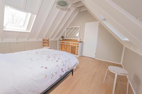 a white bedroom with a bed and a window at Aan `t Krakeel in Noordscheschut