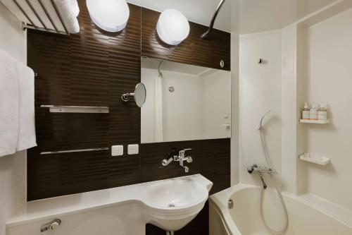 a bathroom with a sink and a toilet and a mirror at Four Points Flex by Sheraton Kanazawa in Kanazawa