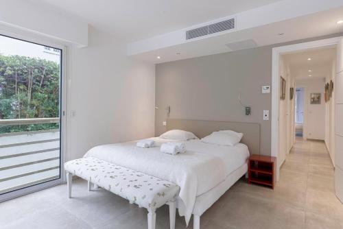 une chambre avec un lit blanc et une grande fenêtre dans l'établissement Jardin d'Azur – Terrace, Calm & Croisette, à Cannes
