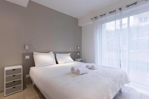 - une chambre blanche avec un grand lit et des serviettes dans l'établissement Jardin d'Azur – Terrace, Calm & Croisette, à Cannes