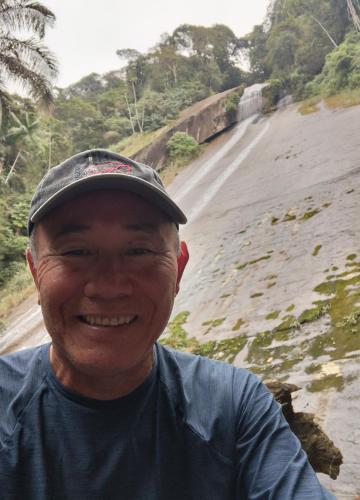 a man wearing a hat standing next to the beach at Pousada Flor de Aurora Bertioga in Bertioga
