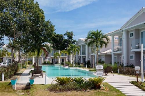 una piscina frente a una casa con palmeras en Flamingo - 4 suite -15 gasten - Arraial d' Ajuda, en Porto Seguro