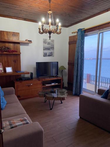 a living room with a couch and a tv and a table at Val's Place in Praia da Vitória