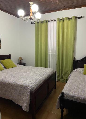 a bedroom with two beds and green curtains at Val's Place in Praia da Vitória