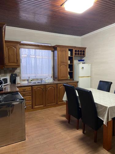 a kitchen with a table and chairs and a table and a refrigerator at Val's Place in Praia da Vitória
