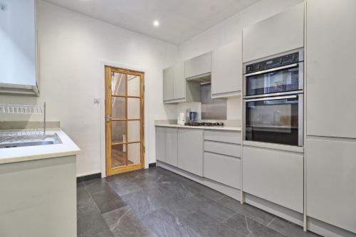 a white kitchen with white cabinets and appliances at Ivy on Sea Villa in Southend-on-Sea