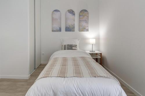 - une chambre blanche avec un lit et deux peintures murales dans l'établissement Résidence de Nogent sur Marne, à Nogent-sur-Marne