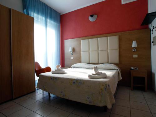 a bedroom with a large bed with a red wall at Hotel Marebello in Rimini