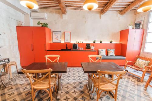 two tables and chairs in a room with orange walls at Le Petit Avignon - chambres & appartement à deux pas du Pont d'Avignon et du Palais des Papes in Avignon