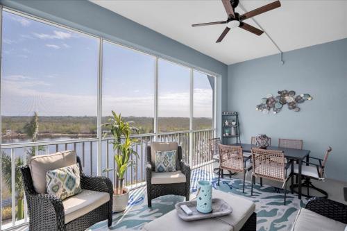 a living room with a balcony with chairs and a table at Latitude Adjustment Penthouse by Coastal Chic in Bradenton