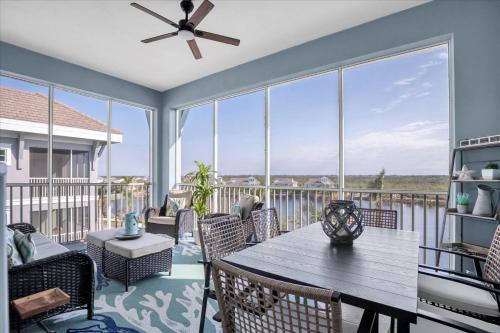 a screened porch with a wooden table and chairs at Latitude Adjustment Penthouse by Coastal Chic in Bradenton