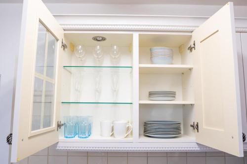 a white cabinet filled with plates and glasses at Modern 2 bed Bromley House in Grove Park
