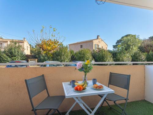 une table avec un vase de fleurs et de fruits sur un balcon dans l'établissement Apartment Les Amandiers by Interhome, à La Seyne-sur-Mer