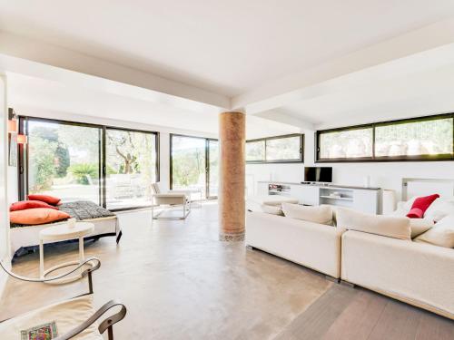 Elle comprend un salon doté d'un mobilier blanc et de grandes fenêtres. dans l'établissement Apartment Villa La Romane by Interhome, à Saint-Tropez