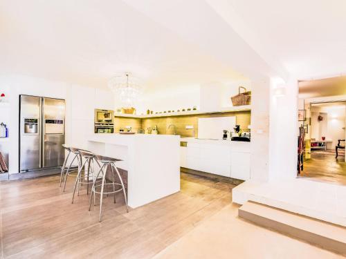 une cuisine avec des armoires blanches et des tabourets de bar dans l'établissement Apartment Villa La Romane by Interhome, à Saint-Tropez