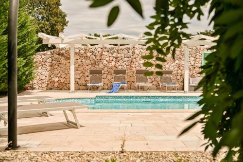 einen Pool mit einer Bank, Stühlen und einer Steinmauer in der Unterkunft Luxury Villa Kras in Dobrinj
