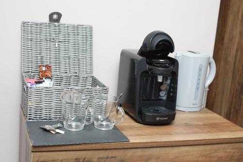 a coffee maker and glasses on a wooden table at OYO Glyn Valley Hotel in Glyn-Ceiriog