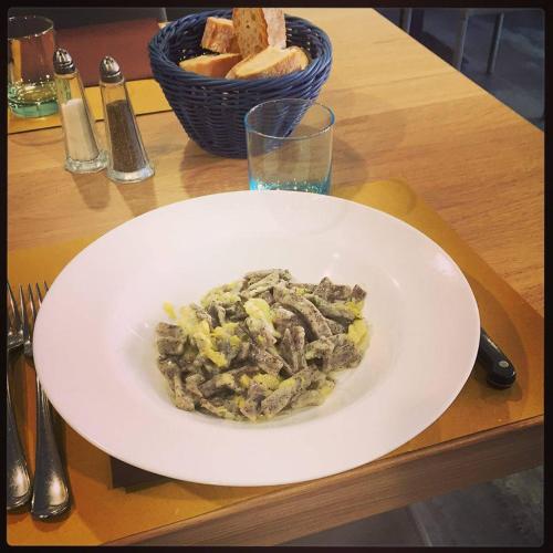 a white plate of food on a table with a glass at Hotel Trieste in Morbegno