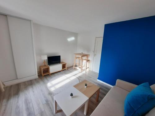 un salon avec un canapé et un mur bleu dans l'établissement Le Perdrix 2 - Studio 2 prs, proche centre ville, à Dijon
