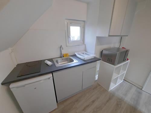 Elle comprend une petite cuisine blanche avec un évier et une fenêtre. dans l'établissement Le Perdrix 2 - Studio 2 prs, proche centre ville, à Dijon