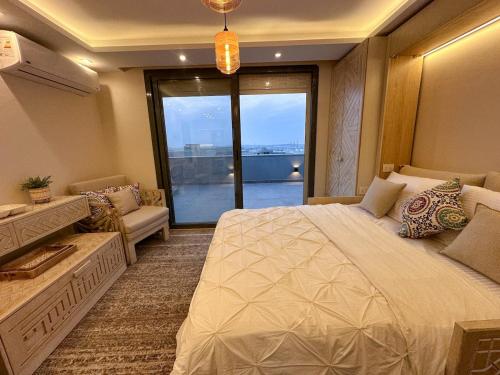 a bedroom with a large bed and a large window at velora Studio roof in sodic villette compound in New cairo