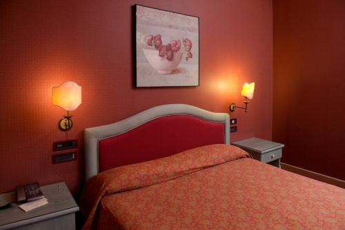 a bedroom with a bed with red walls and two lamps at Hotel Promenade in Montesilvano