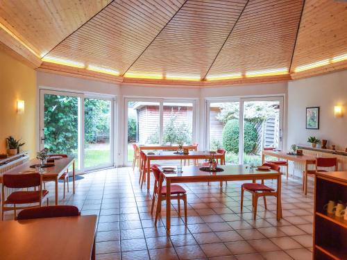 ein Restaurant mit Tischen und Stühlen und Fenstern in der Unterkunft Gästehaus Bleckmar in Bergen