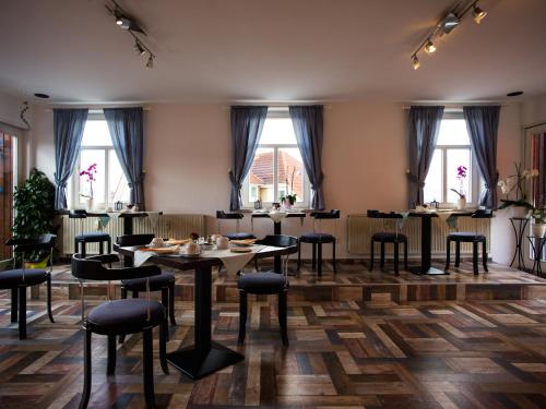 a dining room with tables and chairs and windows at Pension Lausitz in Bautzen