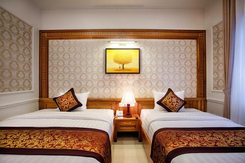 a hotel room with two beds and a picture on the wall at Riverside Hotel Quang Binh in Dong Hoi