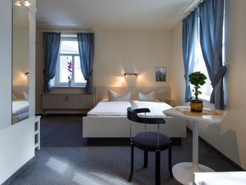 a hotel room with a bed and a table and a desk at Pension Lausitz in Bautzen