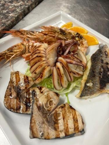 a plate of food with shrimp and other foods at Pausania Inn in Tempio Pausania