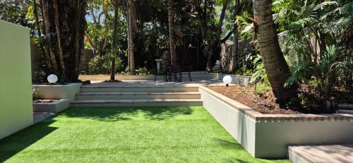 a garden with green grass and stairs and trees at Fairway Lodge in Pongola