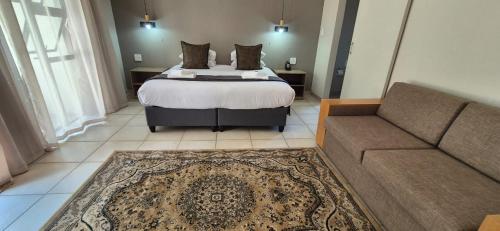 a bedroom with a bed and a couch at Fairway Lodge in Pongola
