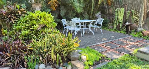 a patio with two chairs and a table in a garden at Fairway Lodge in Pongola