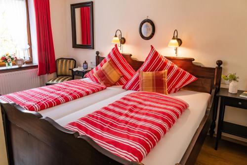 a bed with red and white striped sheets and pillows at Landhaus Wern's Mühle in Ottweiler