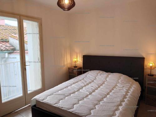 une chambre avec un grand lit et une grande fenêtre dans l'établissement 4DEMO46 - Collioure appartement T2 plage et vue, à Collioure