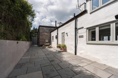 a stone walkway leading to a white building at Tan Y Fron By Birch Stays in Pentraeth